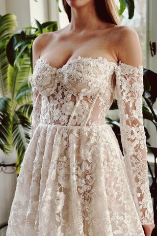 Elegante vestido de novia largo de corte A con hombros descubiertos, encaje y pedrería, con mangas largas.