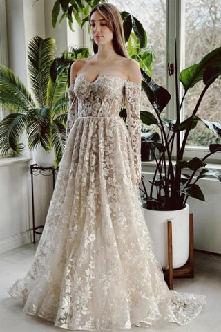 Elegante vestido de novia largo de corte A con hombros descubiertos, encaje y pedrería, con mangas largas.