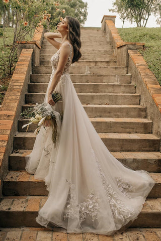 Elegante vestido de novia largo de corte A, sin mangas, con flores y espalda descubierta, adornado con encaje.