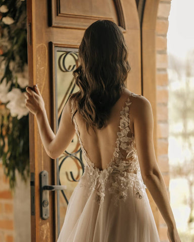 Elegante vestido de novia largo de corte A, sin mangas, con flores y espalda descubierta, adornado con encaje.