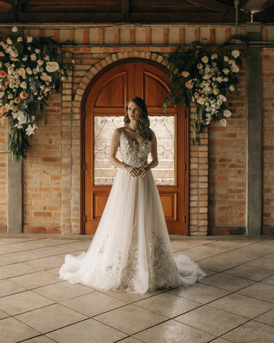 Elegante vestido de novia largo de corte A, sin mangas, con flores y espalda descubierta, adornado con encaje.