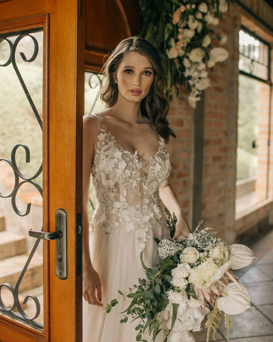 Elegante vestido de novia largo de corte A, sin mangas, con flores y espalda descubierta, adornado con encaje.