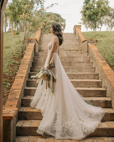 Elegante vestido de novia largo de corte A, sin mangas, con flores y espalda descubierta, adornado con encaje.