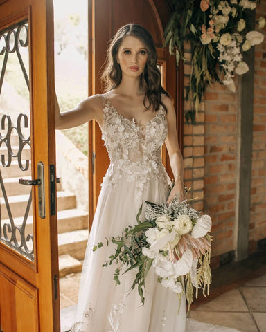 Elegante vestido de novia largo de corte A, sin mangas, con flores y espalda descubierta, adornado con encaje.