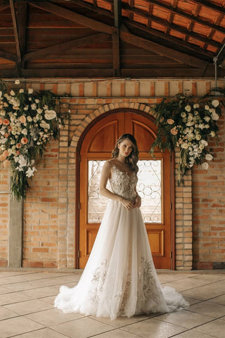 Elegante vestido de novia largo de corte A, sin mangas, con flores y espalda descubierta, adornado con encaje.