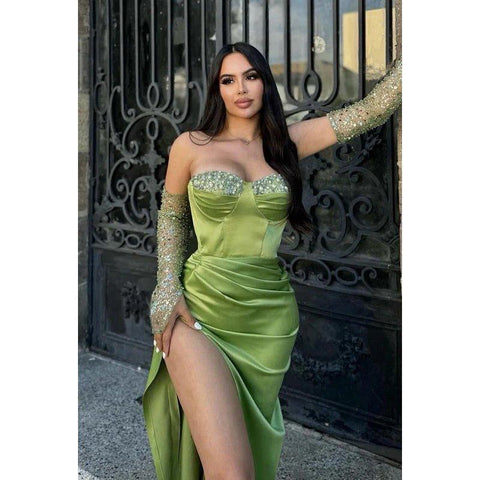 Vestido de graduación elegante y moderno con hombros descubiertos, mangas largas, abertura lateral, fruncido y pedrería.