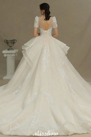 Vestido de novia elegante de manga corta con apliques de tul y encaje, ideal para bodas de primavera en el jardín.