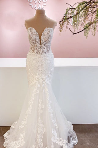 Elegante vestido de novia largo de corte sirena, con escote corazón, espalda descubierta y apliques de encaje.