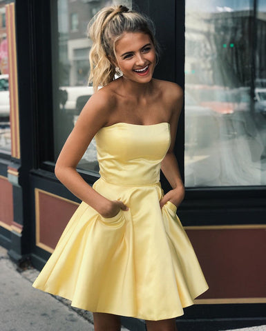 Lindos vestidos cortos de satén amarillo estilo A, sin tirantes, para baile de graduación o fiesta de bienvenida, con bolsillos.