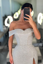 Vestido de fiesta blanco de sirena con lentejuelas, hombros descubiertos y abertura.