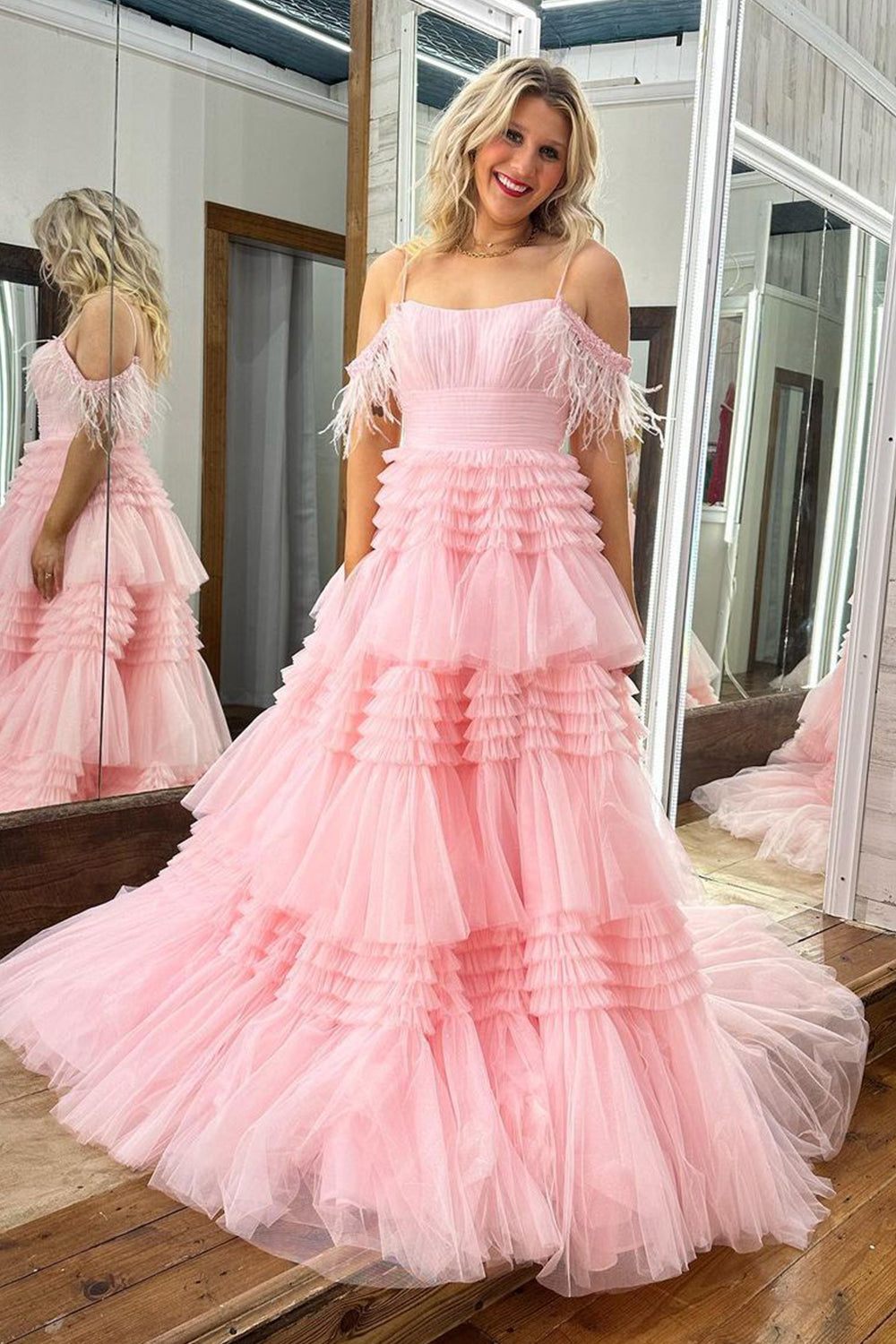 Un vestido largo de fiesta rosa claro con escote barco y plumas