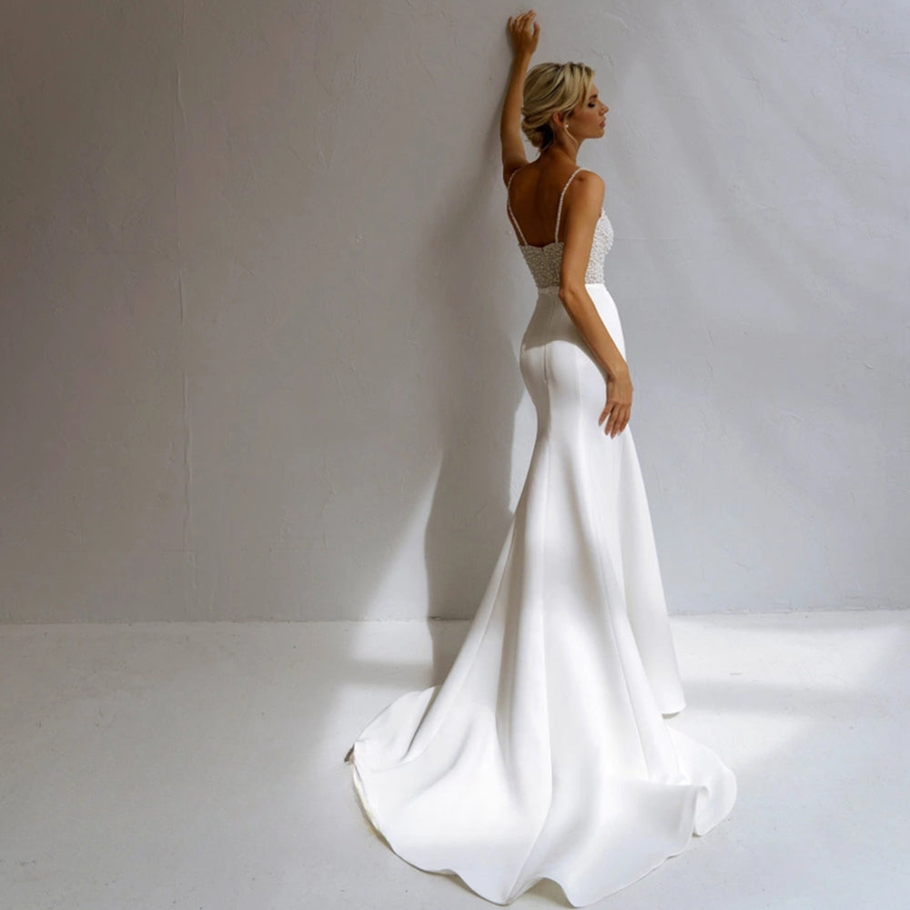 Vestido de novia de corte sirena con perlas, tirantes finos, satén, cuentas y escote en V. 