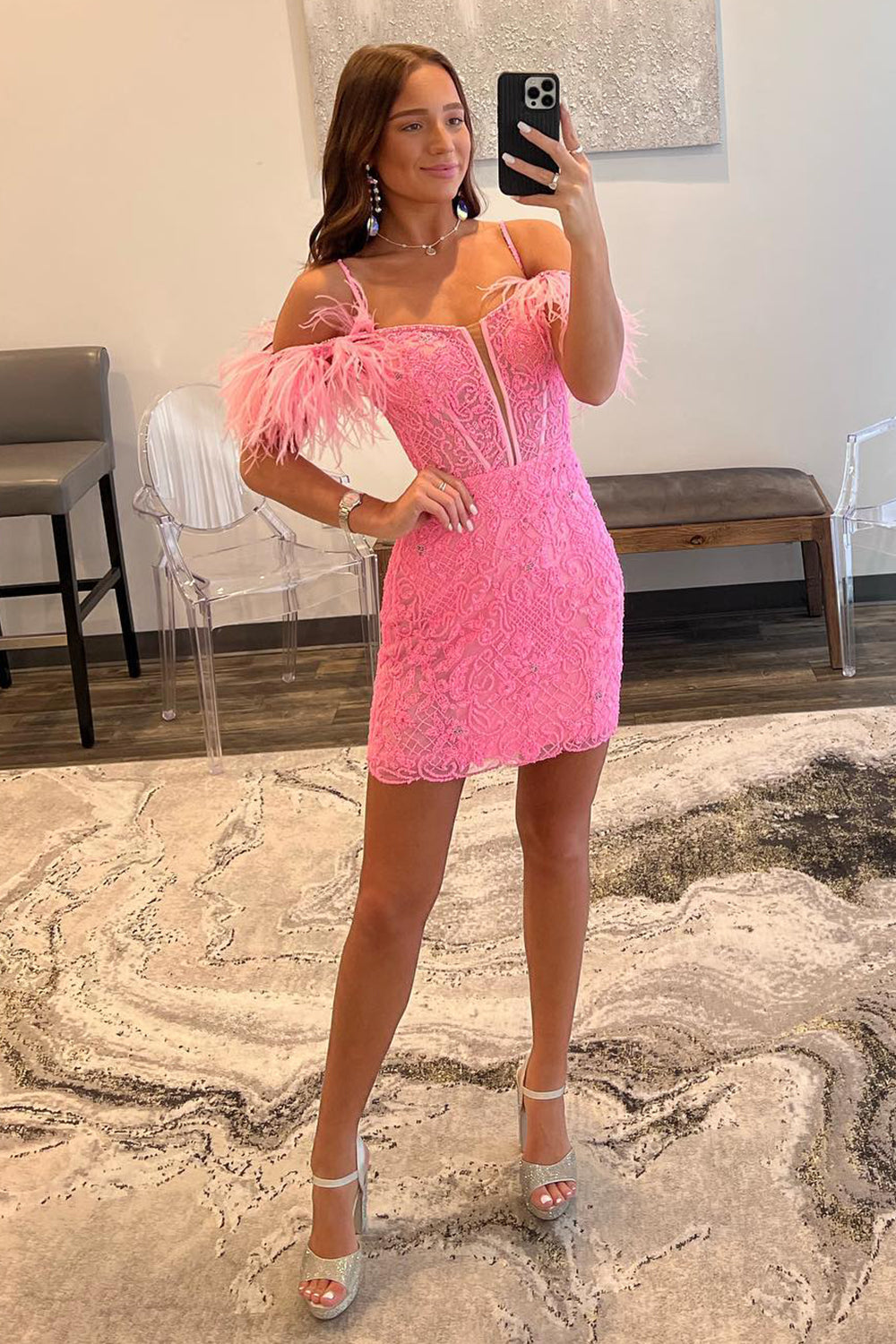 Vestido corto rosa fucsia de corte sirena con hombros descubiertos y detalles de plumas.