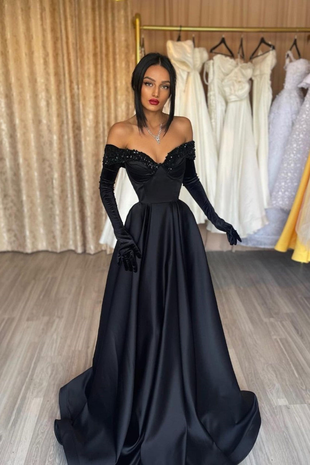 Robe de bal longue noire en satin, coupe trapèze, épaules dénudées, avec gants.