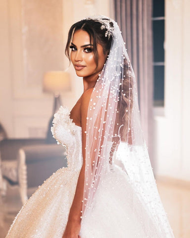 Robe de mariée de luxe longue au sol, décolleté cœur sans manches, coupe trapèze, ornée de sequins et de perles.