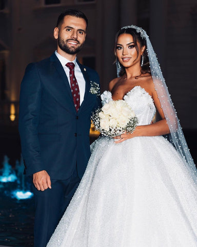 Robe de mariée de luxe longue au sol, décolleté cœur sans manches, coupe trapèze, ornée de sequins et de perles.