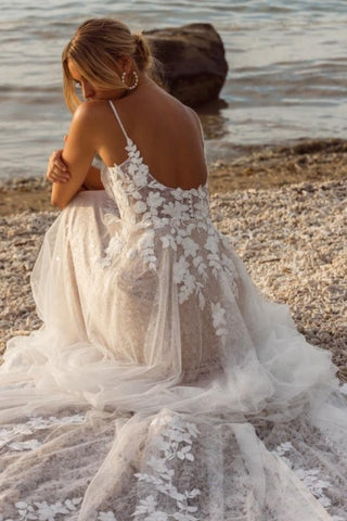Robe de mariée blanche sans manches en dentelle, coupe trapèze, bretelles spaghetti et appliques, ornée de dentelle.