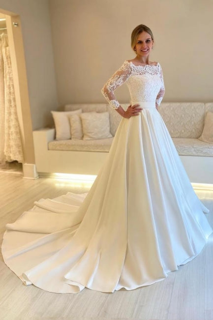Robe de mariée blanche en satin et dentelle, coupe trapèze, manches longues, ornée d'appliqués