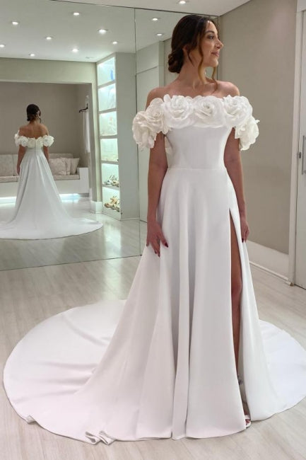Robe de mariée blanche en satin, coupe trapèze, épaules dénudées, sans manches et fendue.