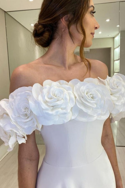 Robe de mariée blanche en satin, coupe trapèze, épaules dénudées, sans manches et fendue.