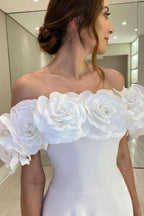 Robe de mariée blanche en satin, coupe trapèze, épaules dénudées, sans manches et fendue.