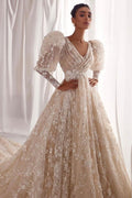 Robe de mariée trapèze en tulle et dentelle, col en V, manches longues, ornée d'appliqués et de volants.