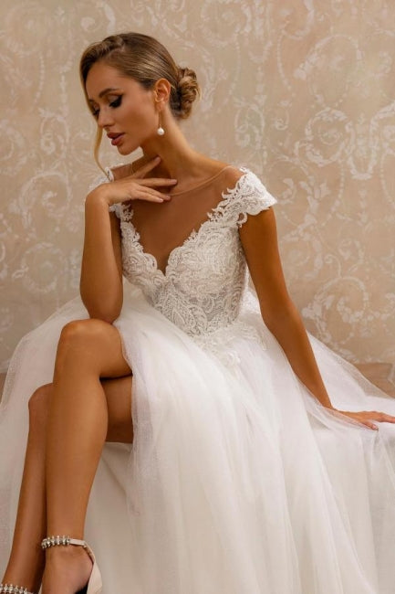 Robe de mariée blanche sans manches en tulle et dentelle, coupe trapèze, col en V, ornée d'appliqués.