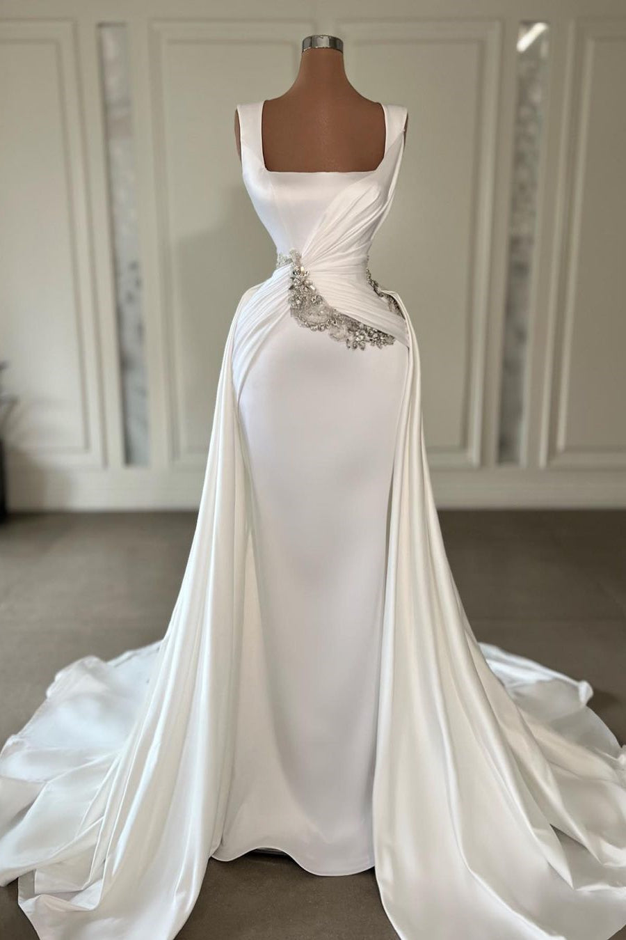Vestido de novia largo de corte A, color marfil, con tirantes, joyas, sin mangas y cola.
