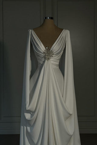 Vestido de novia largo de satén color marfil, corte en A, escote en V y mangas largas.