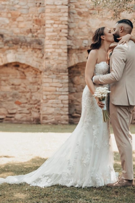 Robe de mariée sirène longue ivoire en dentelle sans bretelles avec traîne.