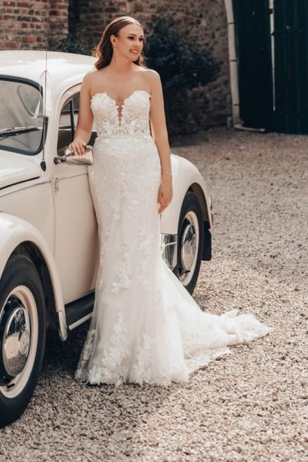 Robe de mariée sirène longue ivoire en dentelle sans bretelles avec traîne.