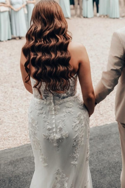 Robe de mariée sirène longue ivoire en dentelle sans bretelles avec traîne.