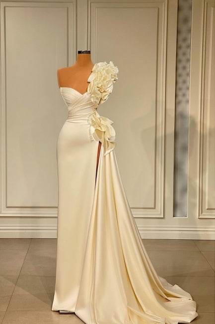 Robe de mariée longue blanche asymétrique à volants et paillettes, ornée d'une épaule dénudée et fendue.