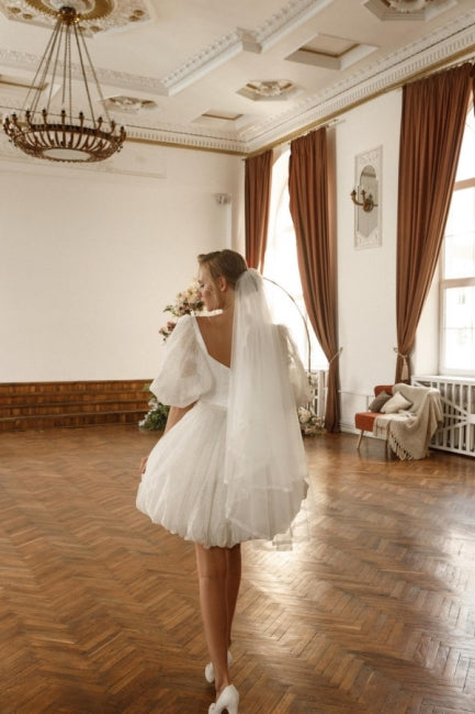 Robe de mariée courte blanche en tulle pailleté à épaules dénudées et manches, signée par un créateur