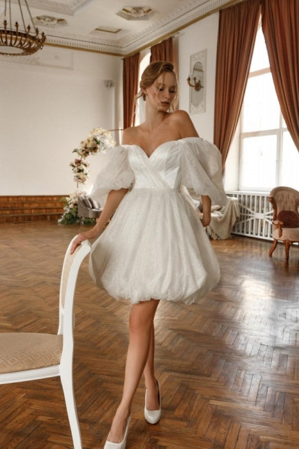 Robe de mariée courte blanche en tulle pailleté à épaules dénudées et manches, signée par un créateur