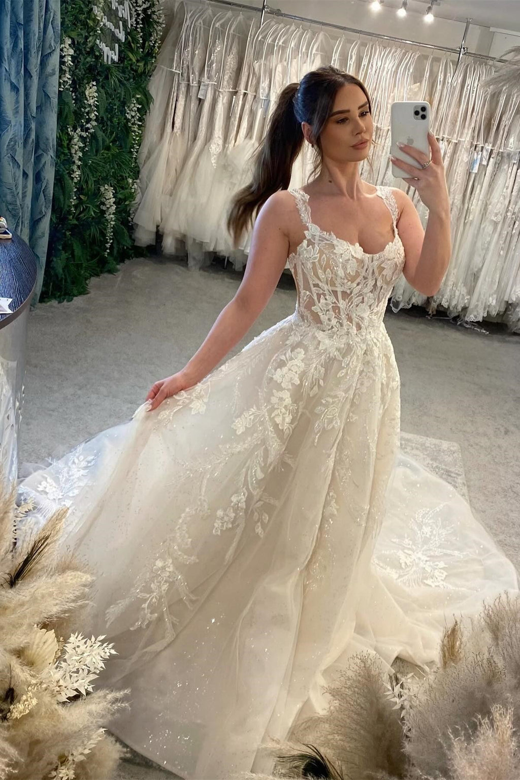 Robe de mariée blanche de créateur, coupe trapèze, bretelles spaghetti, sans manches, en tulle et dentelle.