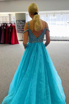 Vestido largo de fiesta azul con escote barco y detalles de pedrería.
