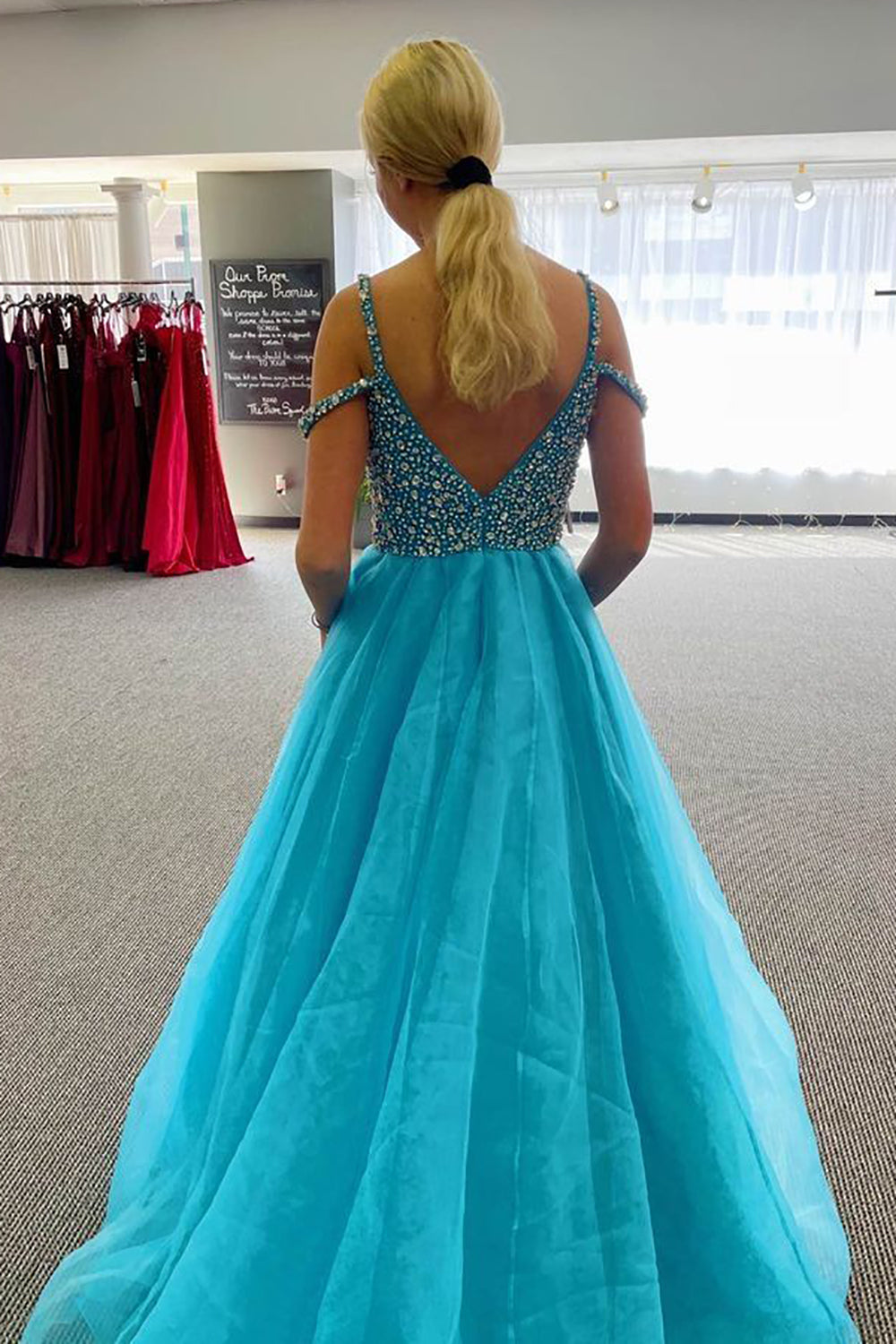 Vestido largo de fiesta azul con escote barco y detalles de pedrería.