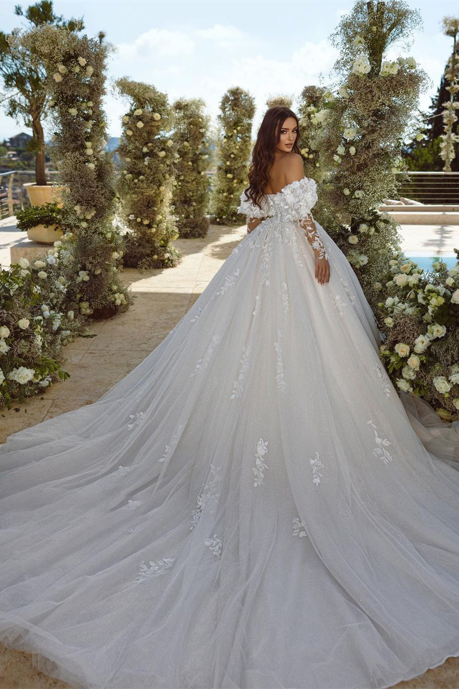 Robe de mariée élégante en tulle, coupe trapèze, ornée d'appliqués de dentelle et décolleté cœur, manches longues