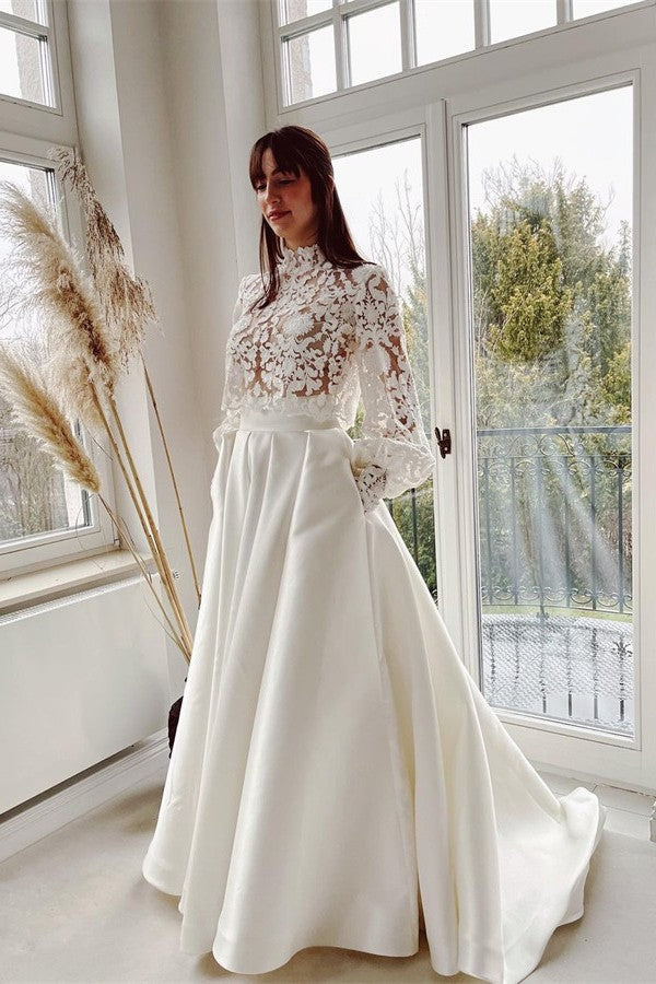Robe de mariée élégante en satin et dentelle, coupe trapèze, col montant, manches longues et poches.