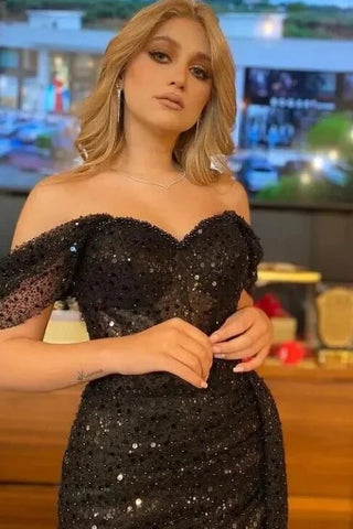 Elegante vestido de fiesta largo negro de sirena con lentejuelas, hombros descubiertos y abertura.