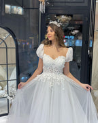 Robe de mariée élégante en tulle, longue jusqu'au sol, décolleté cœur, manches courtes et coupe trapèze, ornée d'une encolure en cœur.