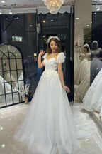 Robe de mariée élégante en tulle, longue jusqu'au sol, décolleté cœur, manches courtes et coupe trapèze, ornée d'une encolure en cœur.