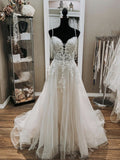 Robe de mariée élégante longue en tulle et dentelle, col en V et bretelles spaghetti, coupe trapèze.