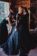 Robe de mariée noire élégante, longue, coupe trapèze, col en V, manches longues et dentelle.