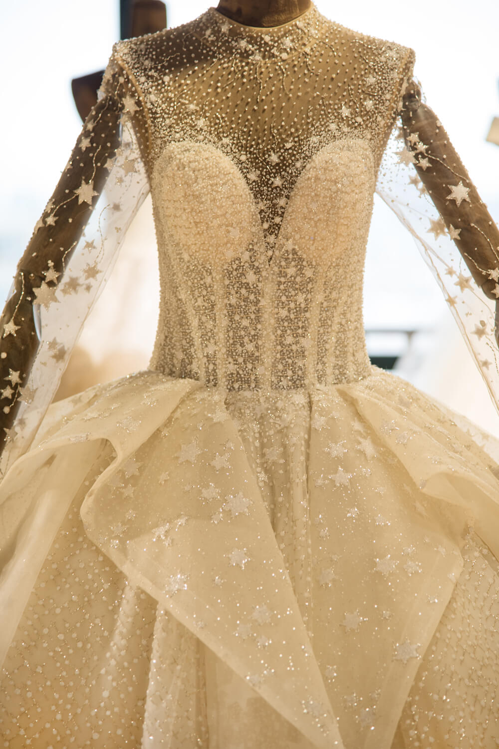 Elegante vestido de novia de tul con mangas largas, bordado con cuentas y cordones, con lentejuelas. 