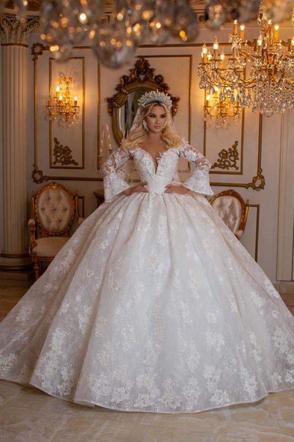 Robe de bal élégante à manches longues, décolleté en V et bustier cœur, ornée d'appliqués de dentelle.
