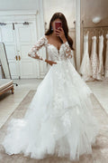 Robe de mariée blanche élégante, longue, de coupe trapèze, à manches longues et ornée d'appliqués et de dentelle.