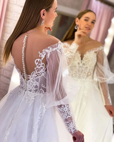 Elegante vestido de novia largo blanco de corte A, escote en V, mangas largas de tul y encaje.