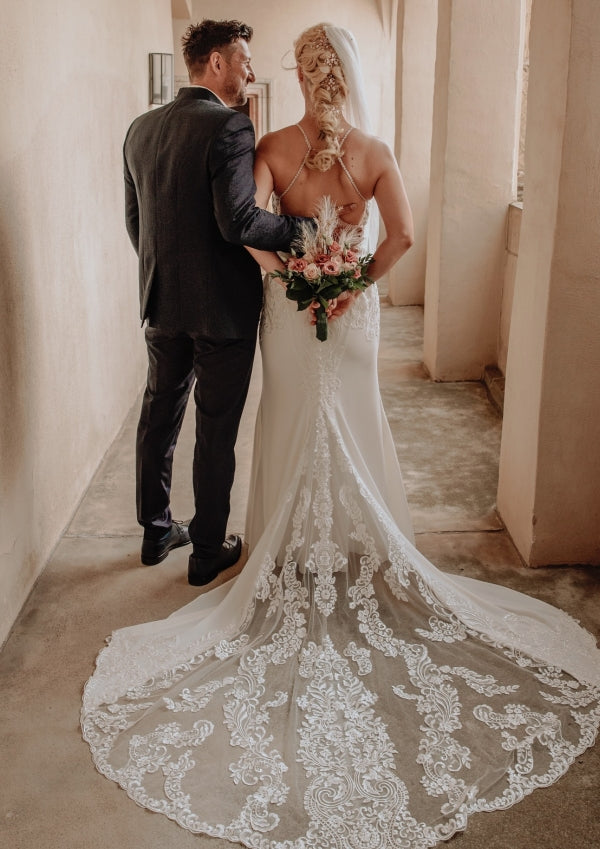 Elegante vestido de novia largo blanco de corte sirena, sin mangas, con espalda descubierta y cola, de encaje.
